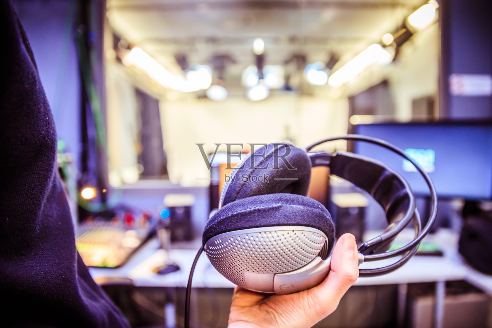 錄音室錄音:一個(gè)戴著耳機(jī)的年輕人正坐在錄音室里,錄音室的背景模糊不清